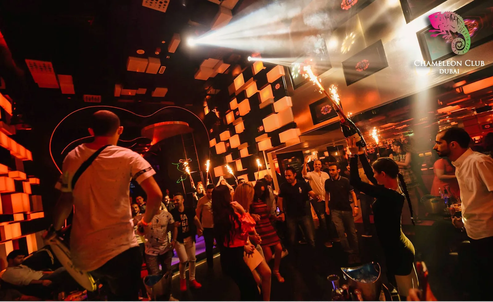 Crowd celebrating on the dance floor with sparklers under amber LED walls at Chameleon Club Dubai