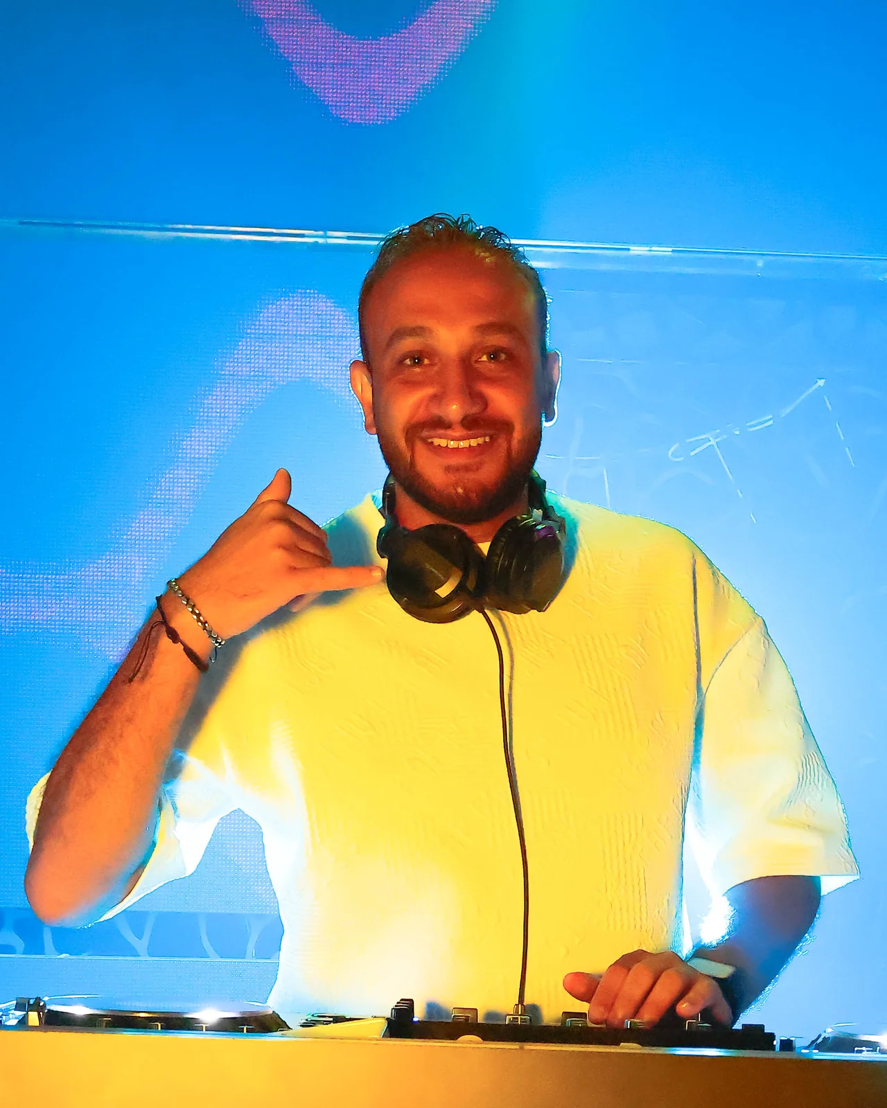 Resident DJ smiling behind the decks under blue light at Chameleon Club Dubai