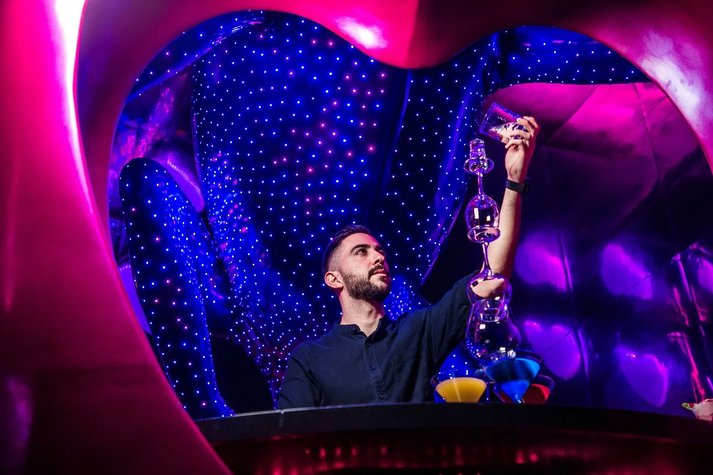 Bartender performing a flair pour beneath the LED chameleon